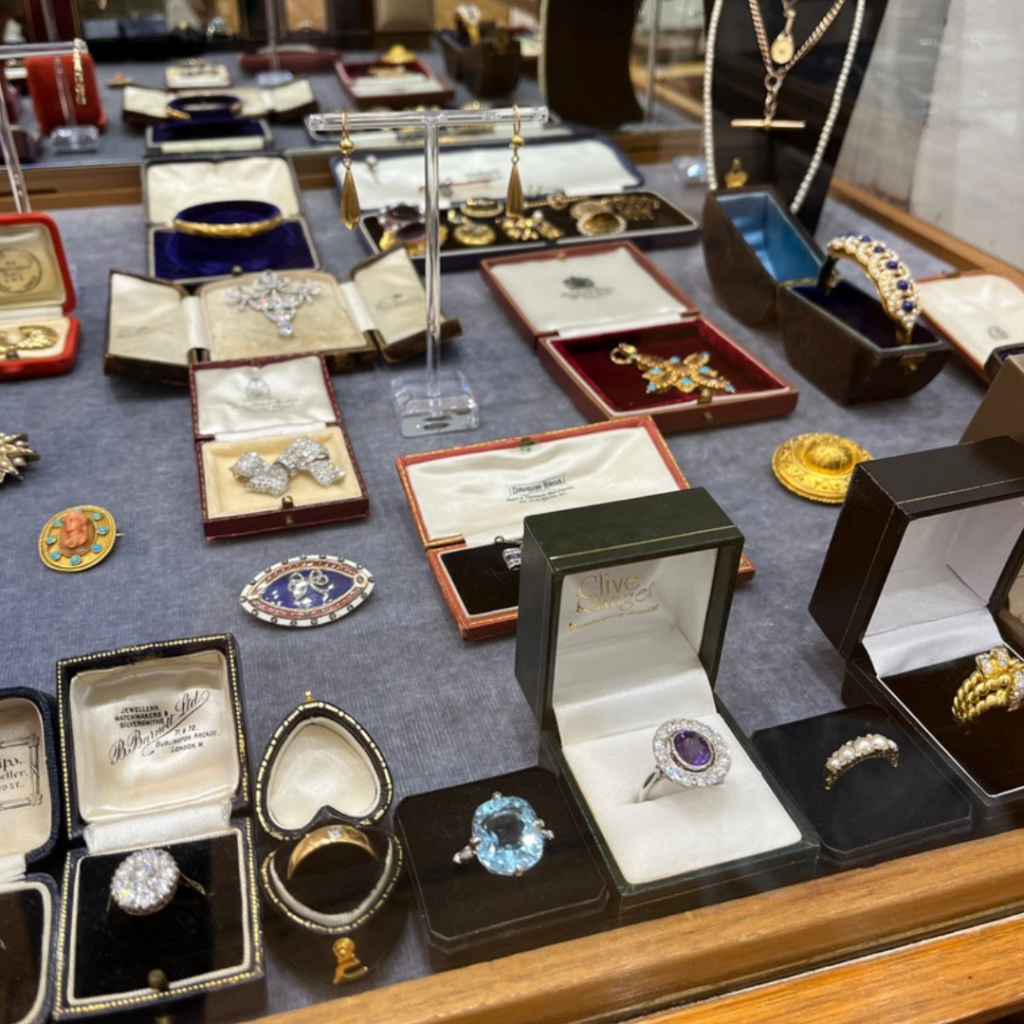 Jewellery in a market stall. Rings in boxes at the front with brooches behind.